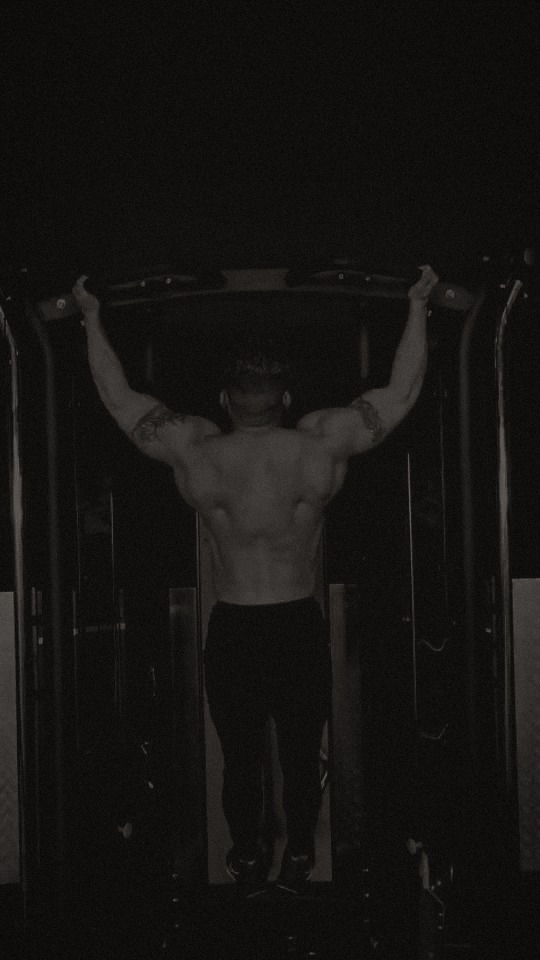 Hussin training pulldowns in a dark gym, black-and-white